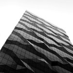 Low-angle view of a modern skyscraper with a geometric glass facade in Melbourne, Australia.
